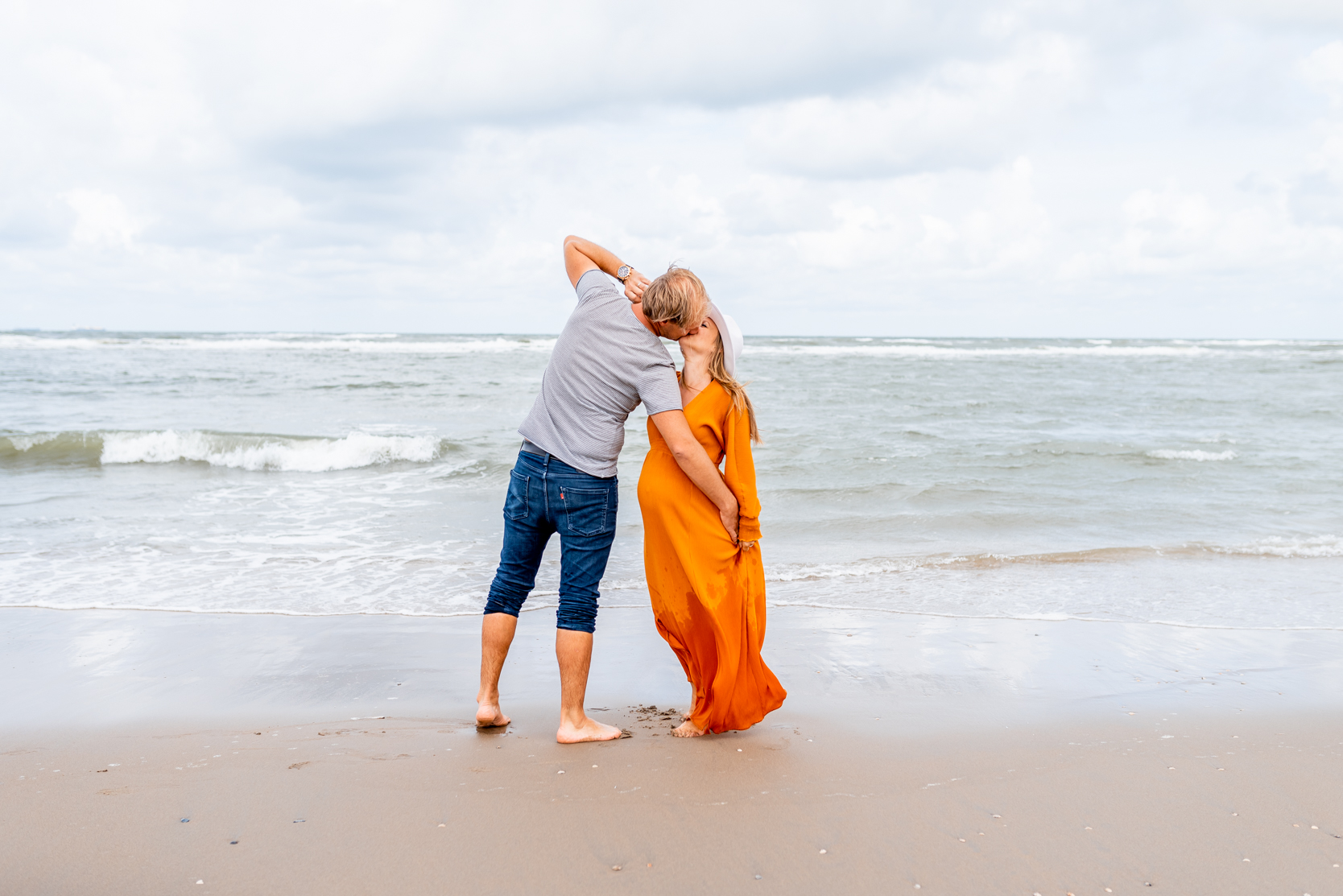 Zwangere vrouw en man dansen op het strand