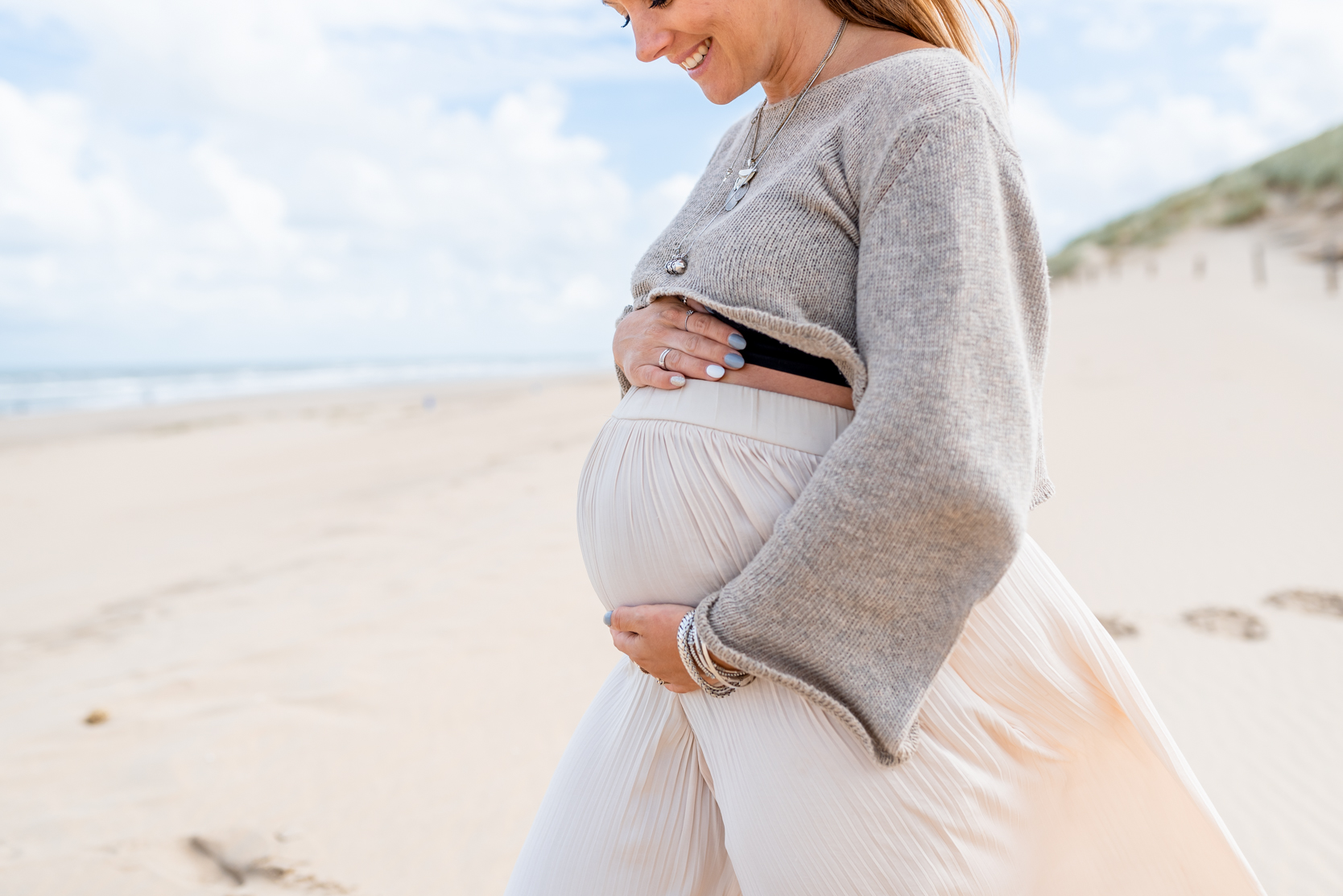 Moeder poseert op het strand met zwangere buik
