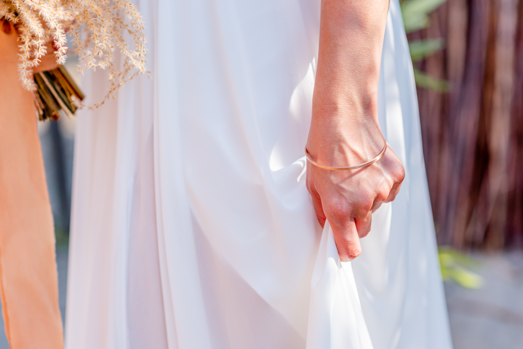 Bruid houdt jurk vast met armband
