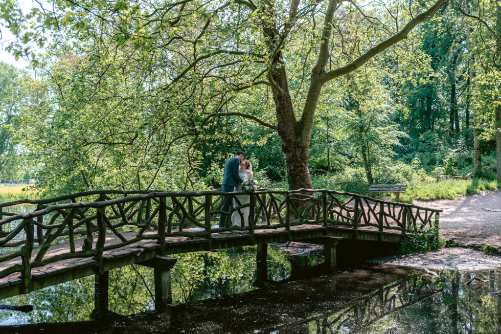 Bruid en bruidegom zoenend op een brug
