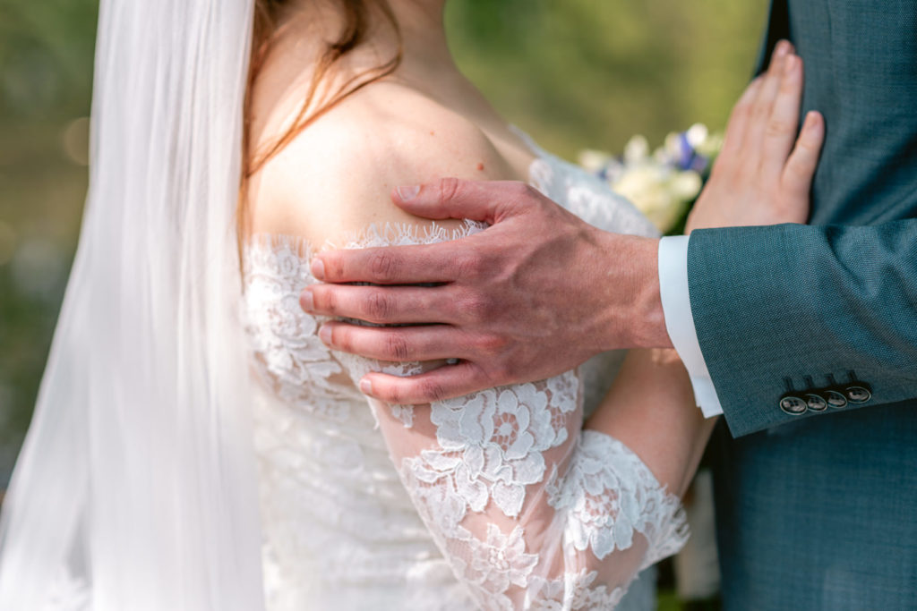 Hand van bruidegom op de schouder van de bruid