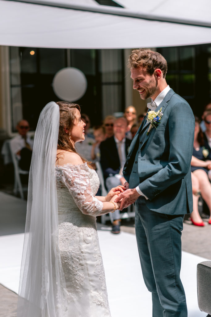 Bruid en bruidegom houden elkaars handen vast voor het ja woord