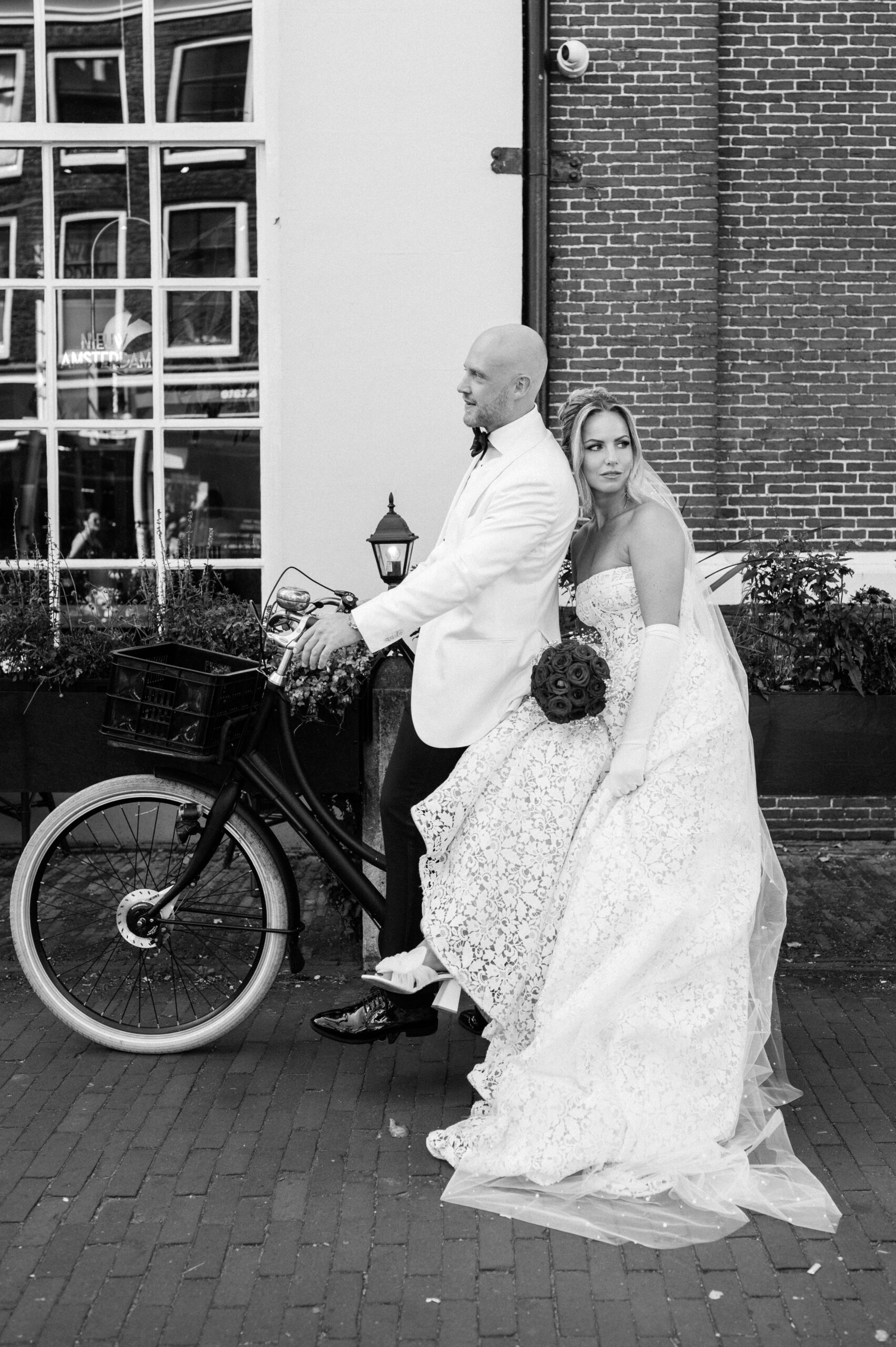 Bruidspaar zit op fiets bij de amsterdamse grachten